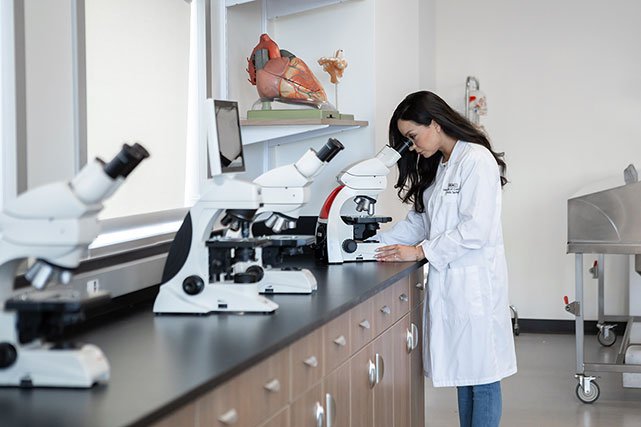UCCS faculty member looking at microscope