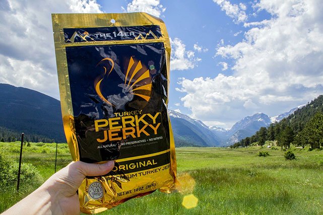Perky Jerky being held in front of mountains