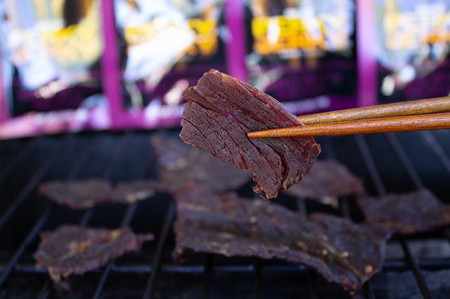 Perky Jerky in chopsticks in front of grill